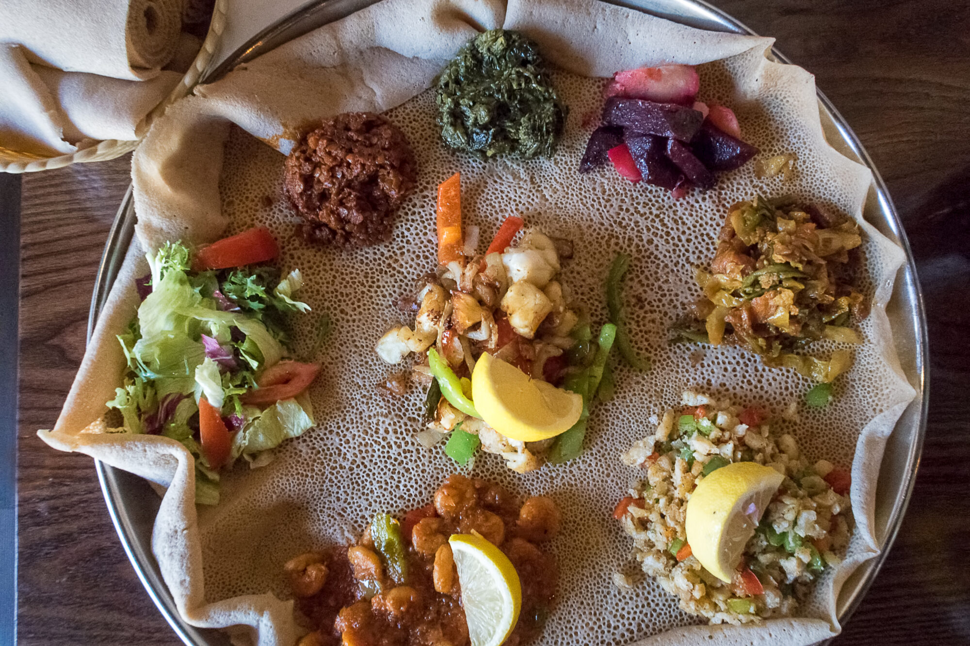 A plate of injera with various toppings, viewed from above.