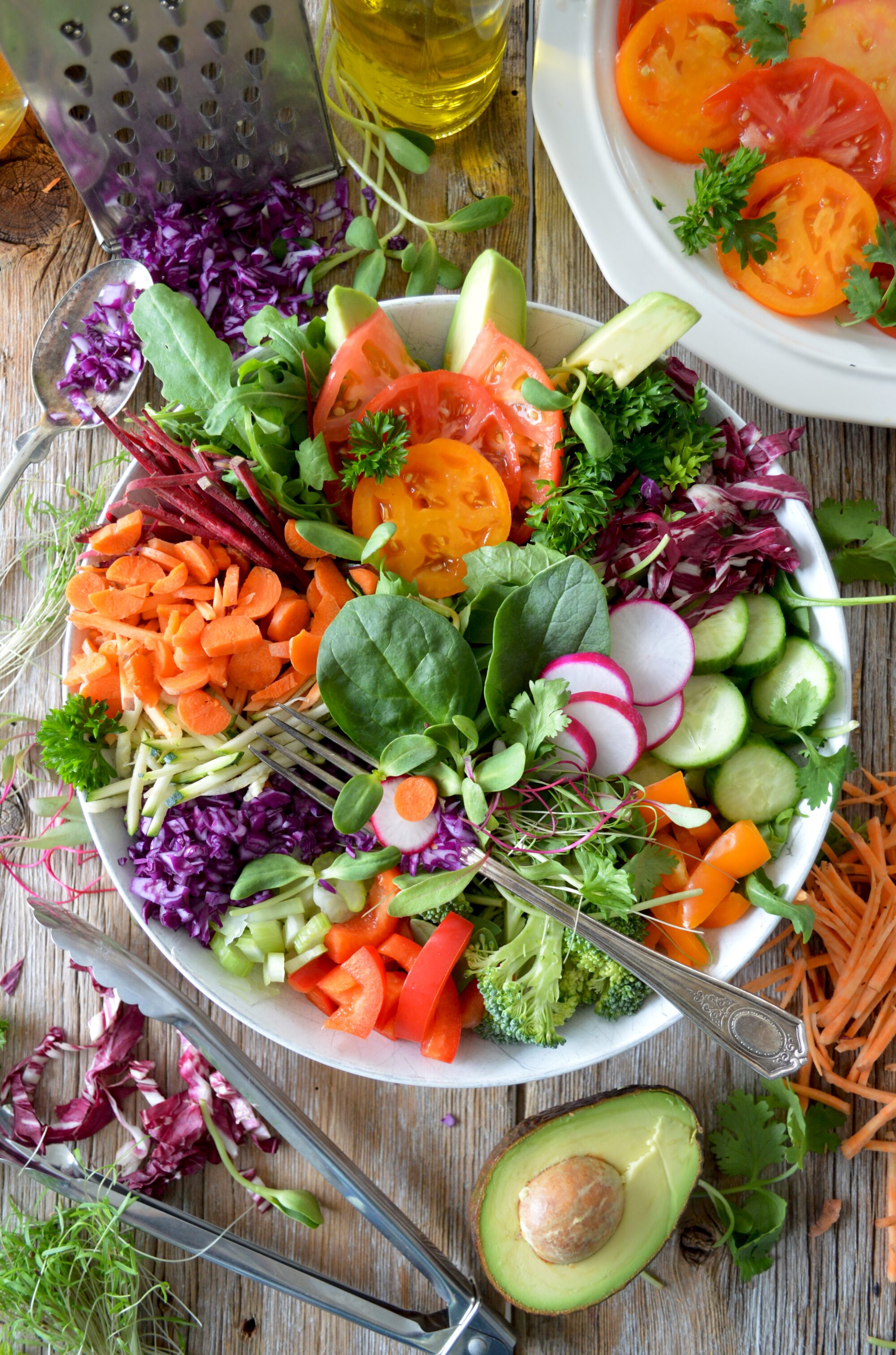 A colorful salad bowl viewed from above, with radishes, broccoli, peppers, cucumbers, sprouts, and many more vegetables.